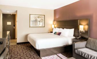 a hotel room with a white bed , a couch , and a tv . also a dining table and chairs in the room at Comfort Inn Largo-Washington DC East