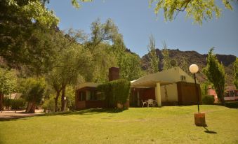 a house surrounded by trees and grass , with a view of the mountains in the background at Cabanas Del Sol