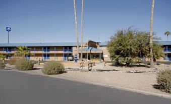"a large building with a sign that reads "" motel "" is surrounded by palm trees and bushes" at Americas Best Value Inn Eloy/Casa Grande