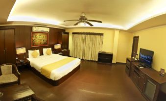 a large bed with a white and yellow comforter is in the middle of a room at Aalankrita Resort and Convention