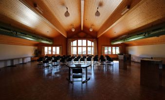 a large , empty room with wooden floors and walls , containing several tables and chairs arranged in a circle at Hotel Roc et Neige