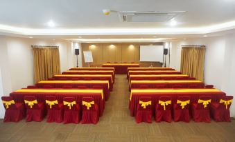 a conference room set up for a meeting , with rows of chairs arranged in front of a projector screen at Kautaman Hotel