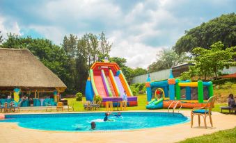 a large inflatable pool with a slide and bouncy house in a grassy area near trees at Silver Springs Hotel