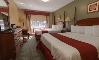 a hotel room with two beds , each made up with white sheets and red comforters , next to a window with curtains at Cumberland Falls State Resort Park