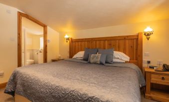 a cozy bedroom with a large bed , a bathroom in the background , and a window providing natural light at The Gwaelod y Garth Inn