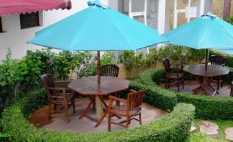 an outdoor dining area with a wooden table and chairs , surrounded by greenery and blue umbrellas at Seulawah Grand View