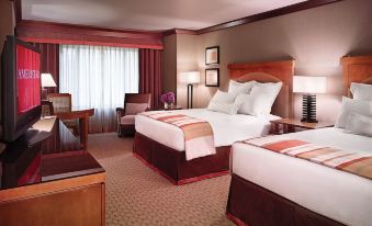 a hotel room with two beds , a desk , and a window , all set against a beige wall at Ameristar Casino Black Hawk