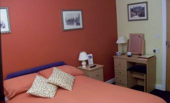 a cozy bedroom with a red bed , orange walls , and a matching nightstand and desk at Thornton Hunt Inn