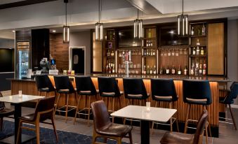 a modern bar with a wooden counter and chairs , surrounded by a dining table and a wine rack at Courtyard New Carrollton Landover