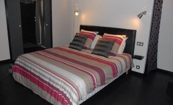 a bed with a striped blanket and two gray pillows is in a room with black flooring at Cleome