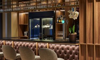 A centrally located bar with ample seating is complemented by a cozy area rug, providing a welcoming ambiance for guests to unwind and savor their beverages at NH Logrono Herencia Rioja