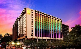 At dusk, a large illuminated building stands against a backdrop of a blue sky at Regal Kowloon Hotel