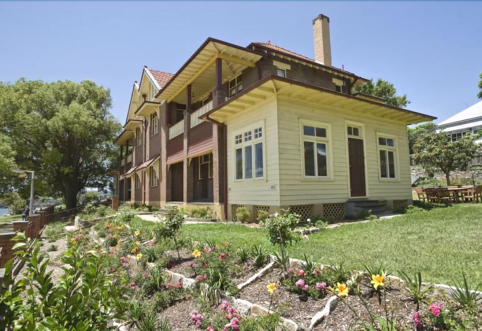 a large house surrounded by a lush green garden , with various flowers and plants in the yard at Cockatoo Island Accommodation