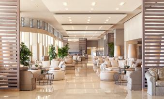 a large , modern hotel lobby with several couches and chairs arranged in a seating area at Sani Beach