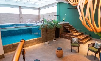 a modern indoor pool area with a staircase leading to the pool , surrounded by potted plants and a chandelier at Nova Hotel