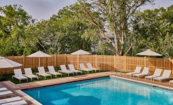 a large swimming pool with white lounge chairs and umbrellas is surrounded by a wooden fence at Block Island Beach House