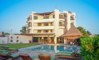 a large , white building with multiple balconies and a swimming pool in front of it , surrounded by greenery at Hotel Rio Lagartos