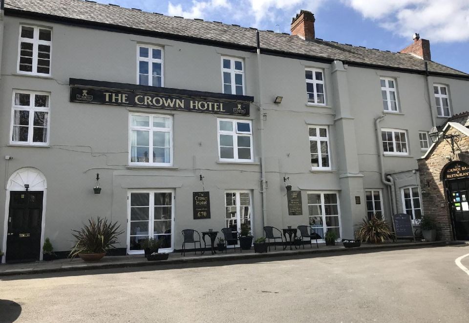"a large building with the name "" the crown hotel "" on it , surrounded by a parking lot" at The Crown Hotel