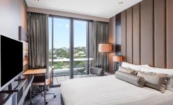 a modern hotel room with a large bed , desk , and sliding glass door leading to a balcony at Gambaro Hotel Brisbane