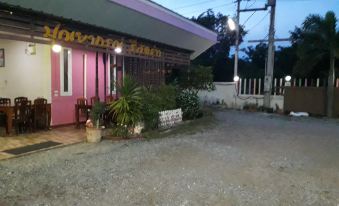 A building on the sidewalk has an umbrella in front of it, adjacent to a small street at Punyaporn Resort