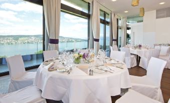 a dining room with tables set for a formal event , featuring white tablecloths and chairs at Belvoir Swiss Quality Hotel