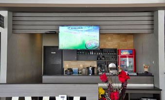 a restaurant with a bar and a television mounted on the wall , displaying a sports game at Grand Krakatau Hotel Serang