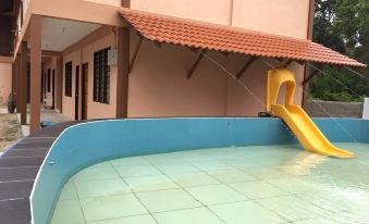 a small blue swimming pool surrounded by a brick house , with a yellow slide attached to it at Nks Chalet