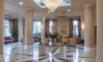 a large , well - lit hotel lobby with marble floors and a crystal chandelier hanging from the ceiling at Hotel Philippos