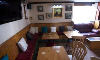 a cozy dining room with wooden tables , chairs , and couches , decorated with framed pictures on the wall at King's Arms
