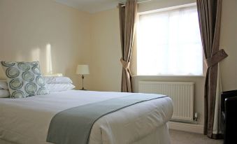 a neatly made bed with white sheets and pillows is situated in a room with a window at Canterbury Hotel