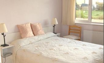 a cozy bedroom with a white bed , two nightstands , and a window looking out to a garden at Ocean Villa