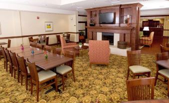 a hotel lobby with a fireplace , dining table , chairs , and a television mounted on the wall at Country Inn & Suites by Radisson, Fredericksburg, VA