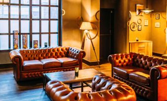 a cozy living room with brown leather couches and chairs arranged in various positions , creating a comfortable seating area at Novotel Leeds Centre