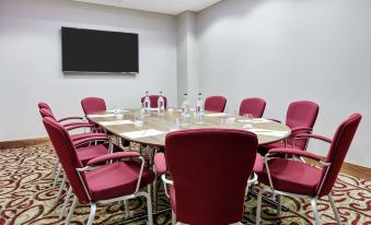 a conference room with a round table surrounded by red chairs and a flat screen tv at Hilton Garden Inn Sunderland