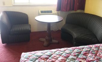 a room with two chairs and a table in the corner , next to a window at H&K Motel
