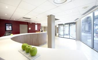 a modern office space with a reception area , an open door leading to the outside , and several green apples on the counter at Campanile Paris Est - Bobigny