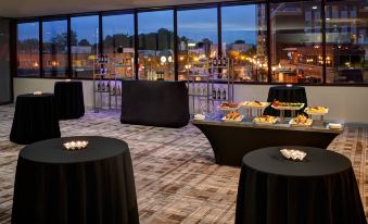a dining room with tables and chairs set up for a party , surrounded by a city skyline at Marriott East Lansing at University Place