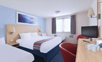 a modern hotel room with two beds , a desk , and a tv , decorated in blue and white colors at Travelodge Peterborough Alwalton