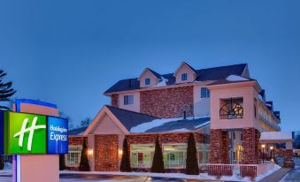 an exterior view of a hotel or motel at night , with a large sign above the entrance at Holiday Inn Express Mackinaw City