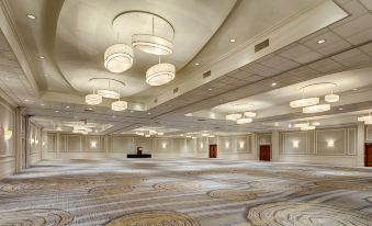 a large , well - lit hotel lobby with a grand piano in the center , surrounded by chairs and tables at Hilton Albany