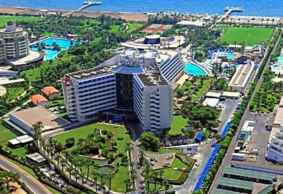 a large hotel surrounded by green grass , trees , and a body of water , providing a picturesque view at Titanic Deluxe Lara