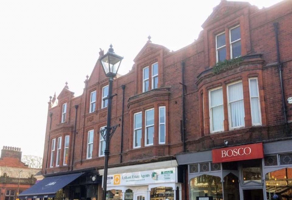a red brick building with multiple windows and balconies , situated on a street corner in a city at Mode Hotel Lytham