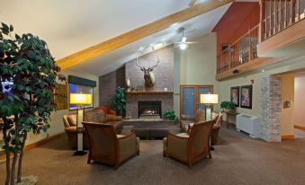 a cozy living room with multiple couches , chairs , and a fireplace , creating a warm and inviting atmosphere at AmericInn by Wyndham Valley City Conference Center