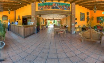 a spacious , well - lit living room with an arched entryway and a mural on the wall at Hotel Hacienda
