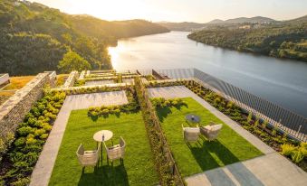 a large outdoor patio with a table and chairs is overlooking a river and mountains at Octant Douro