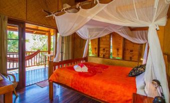 a cozy wooden cabin with a bed , canopy , and balcony , decorated with white curtains and red flowers at 1770 Beach Shacks