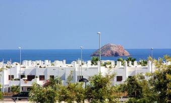 a row of white buildings with satellite dishes on the roofs , overlooking a clear blue ocean and a small island in the distance at Casa Blanca