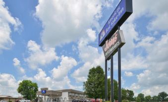 a large building with a blue and white sign on top of it , surrounded by trees at SureStay Hotel by Best Western Bowling Green North