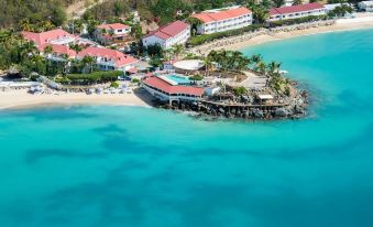 aerial view of a tropical island with white buildings , blue water , and palm trees , surrounded by white sandy beaches at Grand Case Beach Club