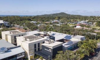 aerial view of a city with buildings , trees , and a view of the ocean in the distance at YHA Byron Bay